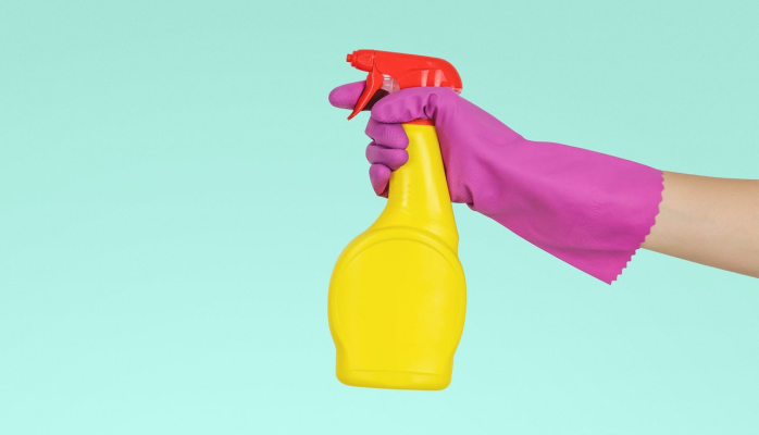 Person-holding-a-yellow-cleaning-spray-bottle